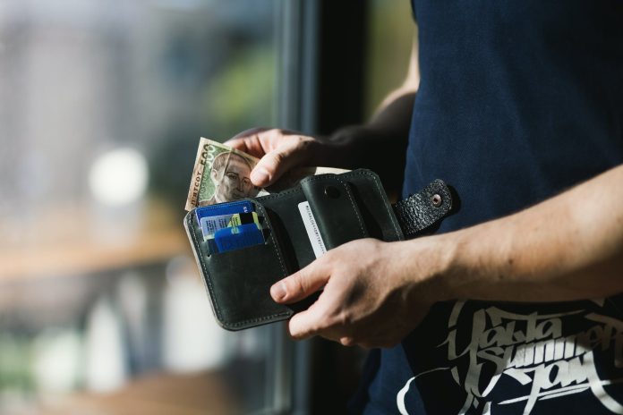 pexels-photo-1174750 photograph of person holding black leather wallet with money