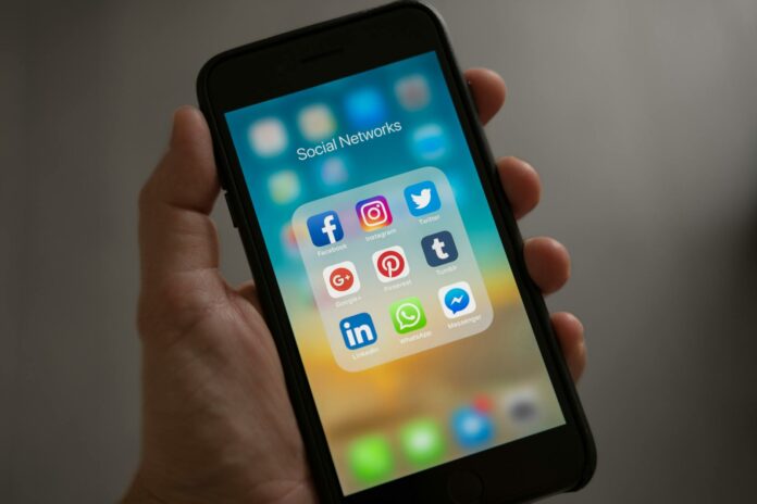 pexels-photo-607812 person holding iphone showing social networks folder