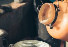 close up of milk being poured into a metal container