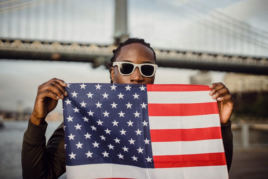 young african american male with american flag bandana against bridge