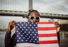 young african american male with american flag bandana against bridge