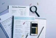 Empresas têm até sexta-feira para entregar informe dos rendimentos de 2025 ao trabalhador a mobile phone and documents near the magnifying glass on the table