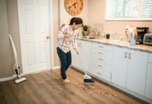 photograph of a woman in a plaid shirt sweeping with a white broom