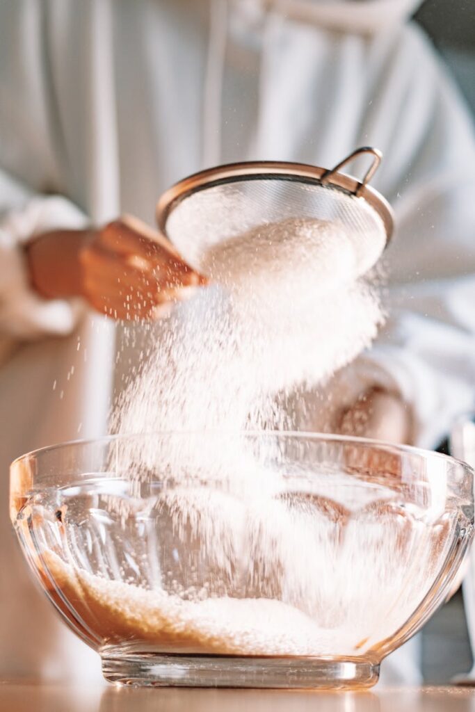 a person sifting powder into a bowl
