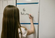 girl writing a message against bullying on a white board