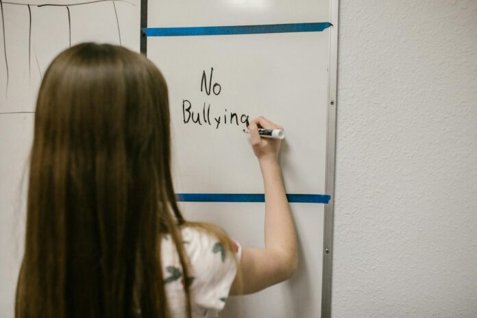 girl writing a message against bullying on a white board