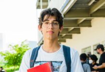 young hispanic student outdoors with notebook