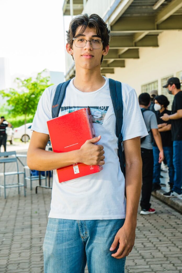 young hispanic student outdoors with notebook
