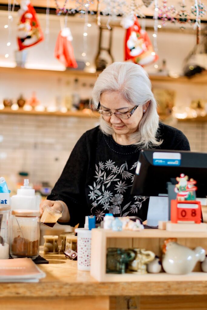elderly woman working at a cozy coffee shop counter