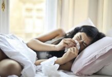 woman lying on bed while blowing her nose
