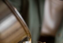 a person pouring candle wax in the glass