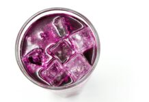 a purple colored drink with ice cubes in a glass