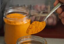 Ferver cúrcuma em pó: para que serve e por que tomar a person is using a spoon to scoop out some orange powder