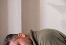 exhausted man resting head on laptop at office desk