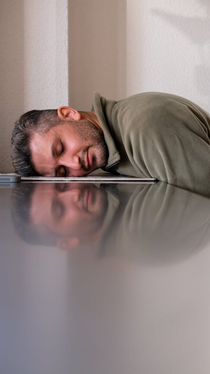 exhausted man resting head on laptop at office desk