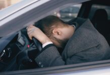 stressed man in car resting on steering wheel