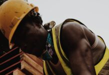 focused black man hammering nail working in construction site