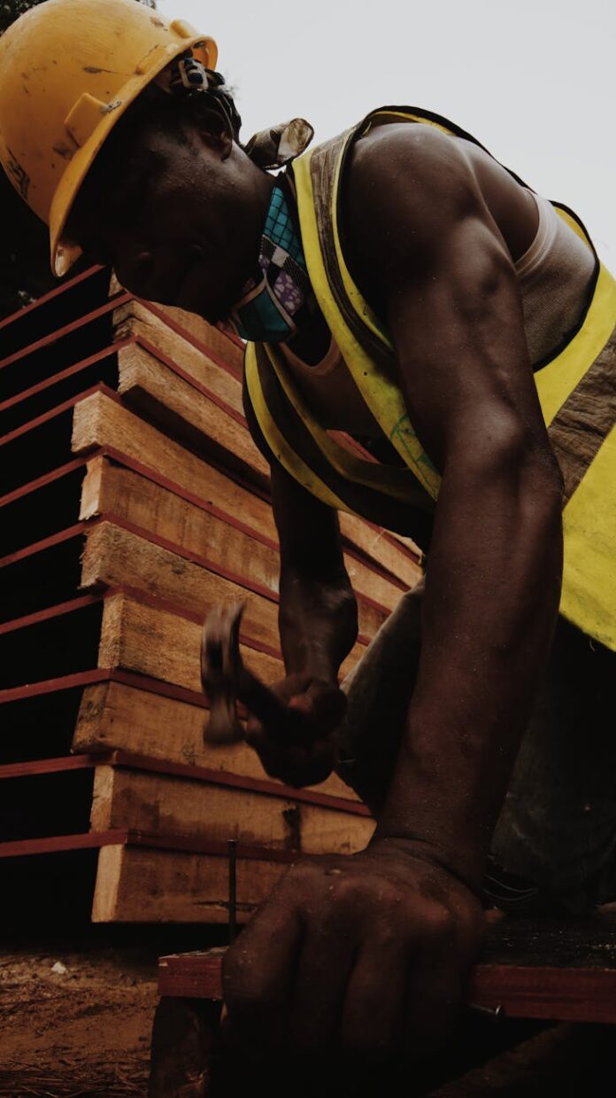 focused black man hammering nail working in construction site