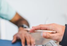 a person holding a pen above a calculator