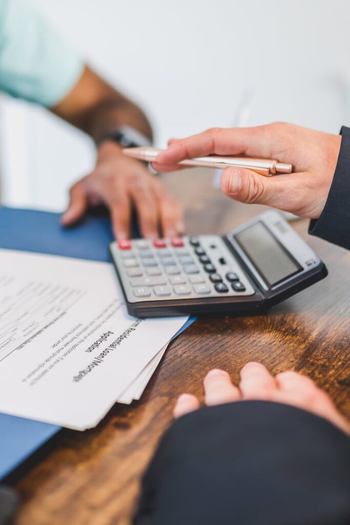 a person holding a pen above a calculator