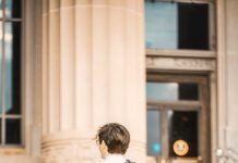 man wearing a suit and holding biretta in front of university