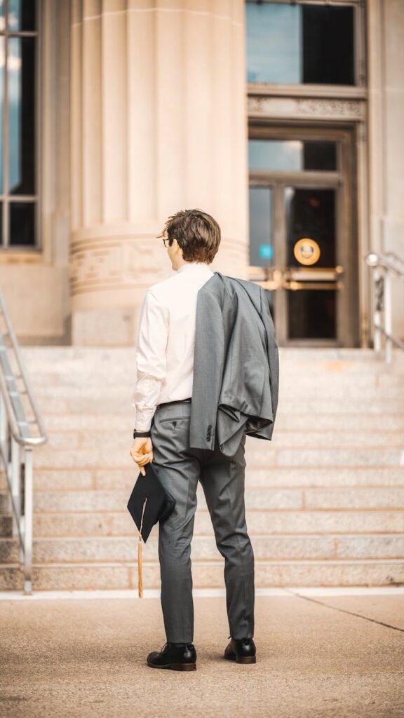 man wearing a suit and holding biretta in front of university