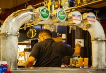 Bares e restaurantes brasileiros acreditam em faturamento recorde na Copa do Mundo bartender serving drinks at a busy bar